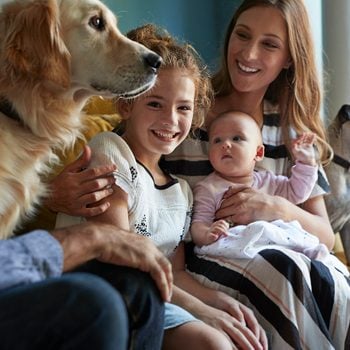 Family Sitting Together In Sofa With Their Dogs