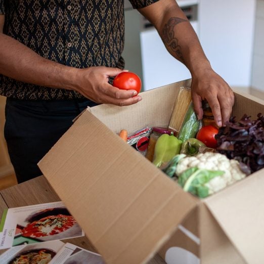 Latin Man Opening Parcel With Meal Kit